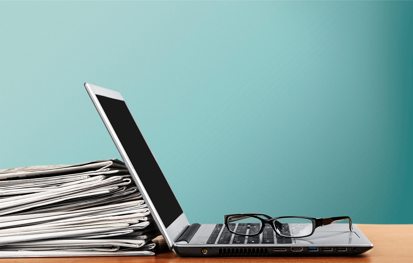 Laptop und Kataloge auf einem Tisch mit Brille daneben